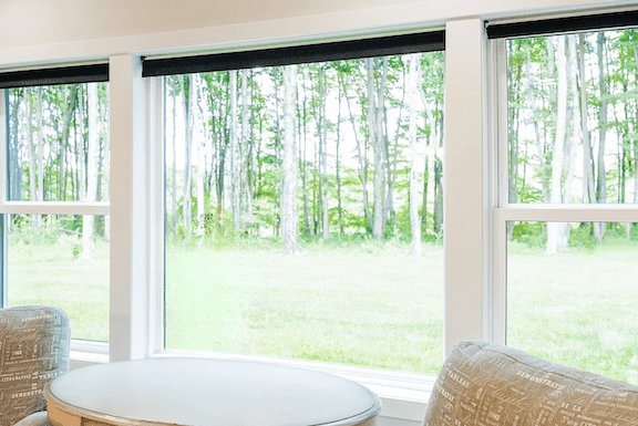 Large residential picture window facing a wooded yard