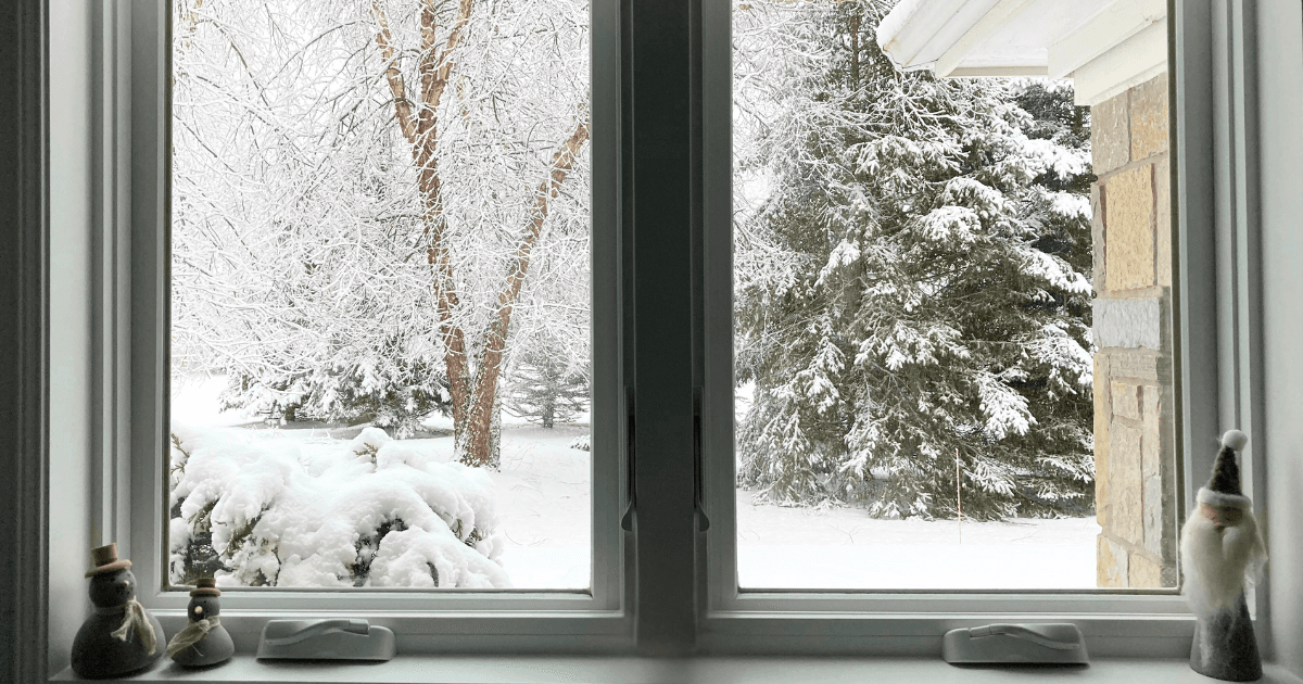 Clear interior home window looking out to a winter, snowy scene