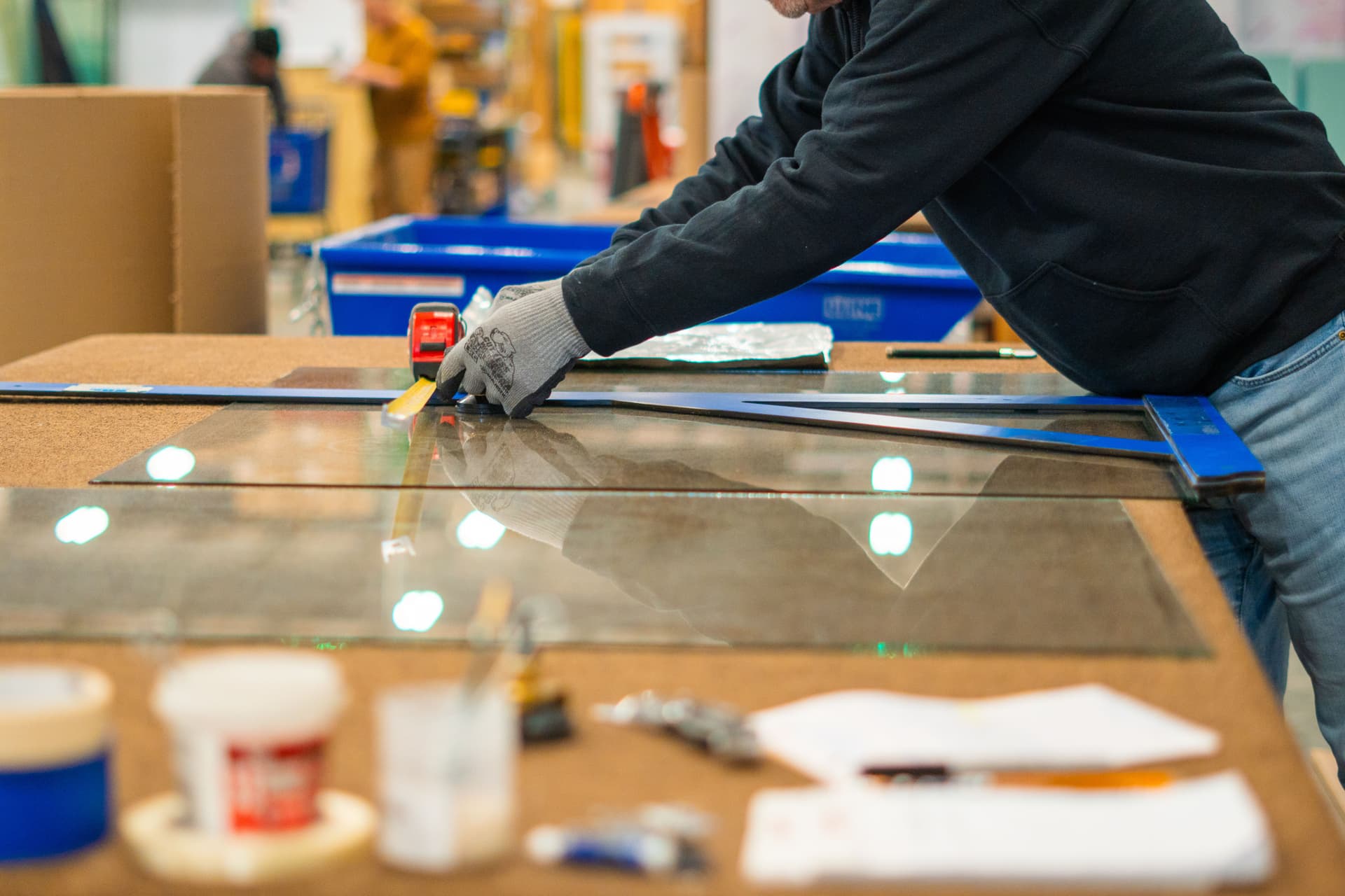 Employee measuring a sheet of glass to prep for cut